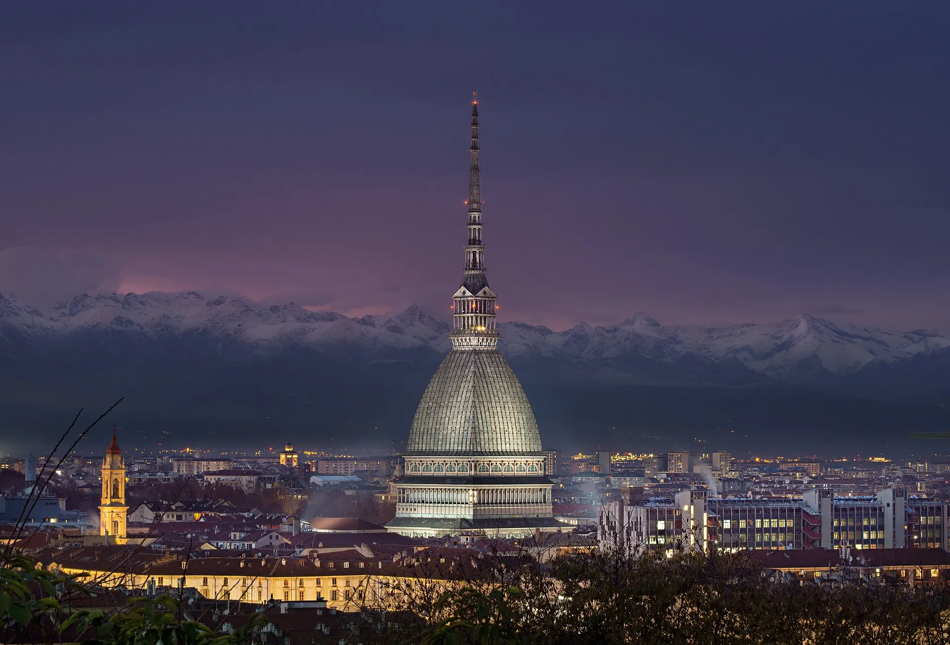 La Mole Antonelliana illuminata di sera con le Alpi innevate sullo sfondo